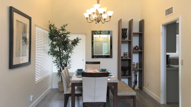 A dining area with a table, chairs, a chandelier, a potted plant, and a mirror.