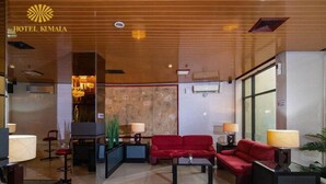 Un vestíbulo de hotel con techo de madera, sofás rojos y una pared de vidrio.