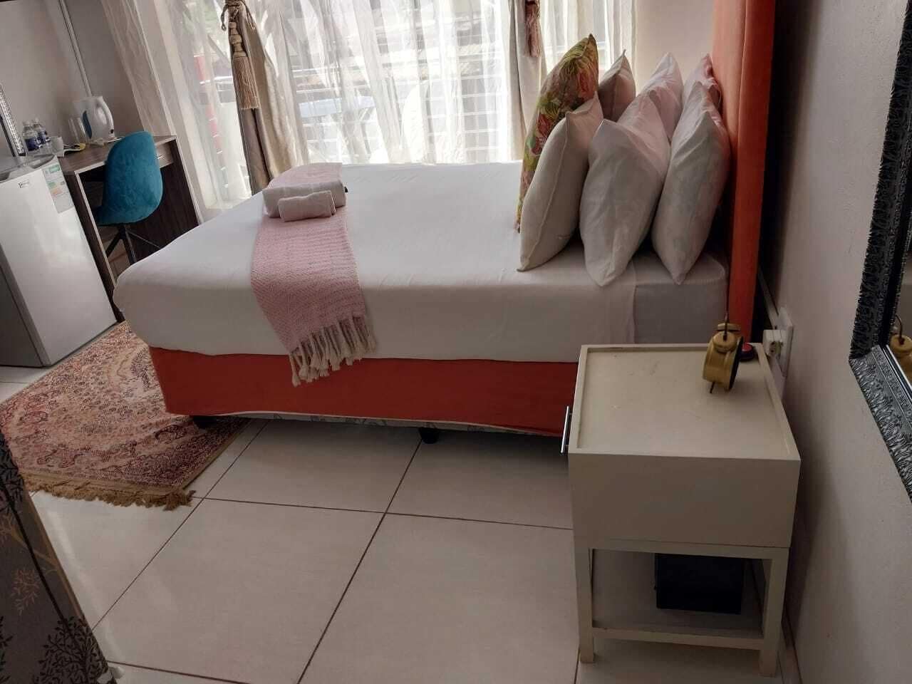 A bedroom with a bed, bedside table, and a small window with curtains.