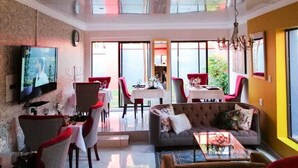 Un amplio salón con sofá, televisión y comedor con sillas rojas y mesa.
