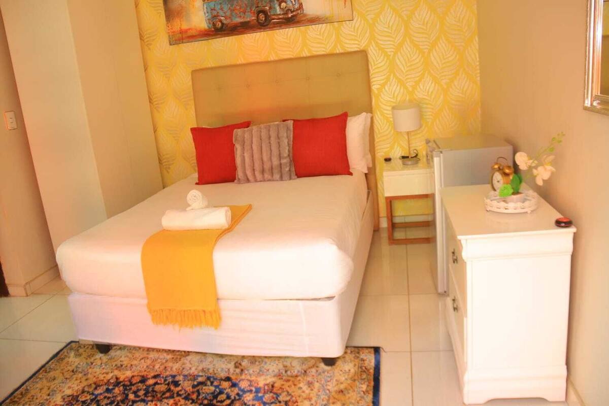 A neatly arranged bedroom with a bed, bedside table, and a small nightstand.