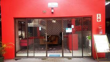 Un espace d’accueil à l’extérieur rouge, doté de portes vitrées et d’une enseigne indiquant qu’il s’agit de la réception.