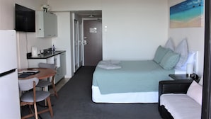 Une chambre d’hôtel avec un lit, un bureau, une chaise et un téléviseur.