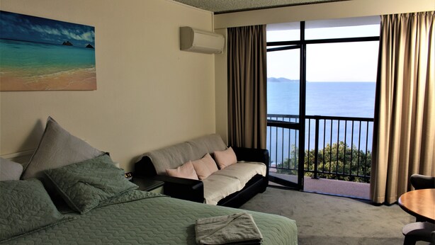 Une chambre d’hôtel comprenant un lit, un canapé, un balcon avec vue sur la mer et une table à manger.