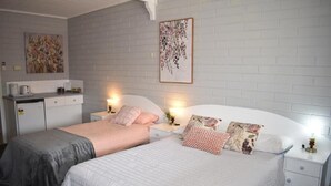 Un dormitorio con dos camas, paredes blancas y obras de arte.