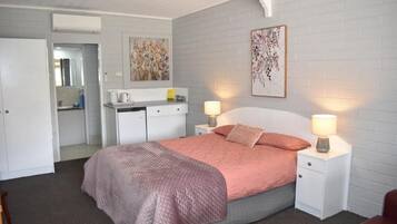 A bedroom with a bed, bedside tables, a nightstand, a desk, and a mirror.