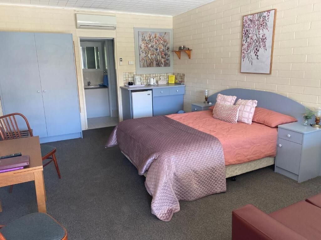 A bedroom with a bed, bedside table, and a desk area.