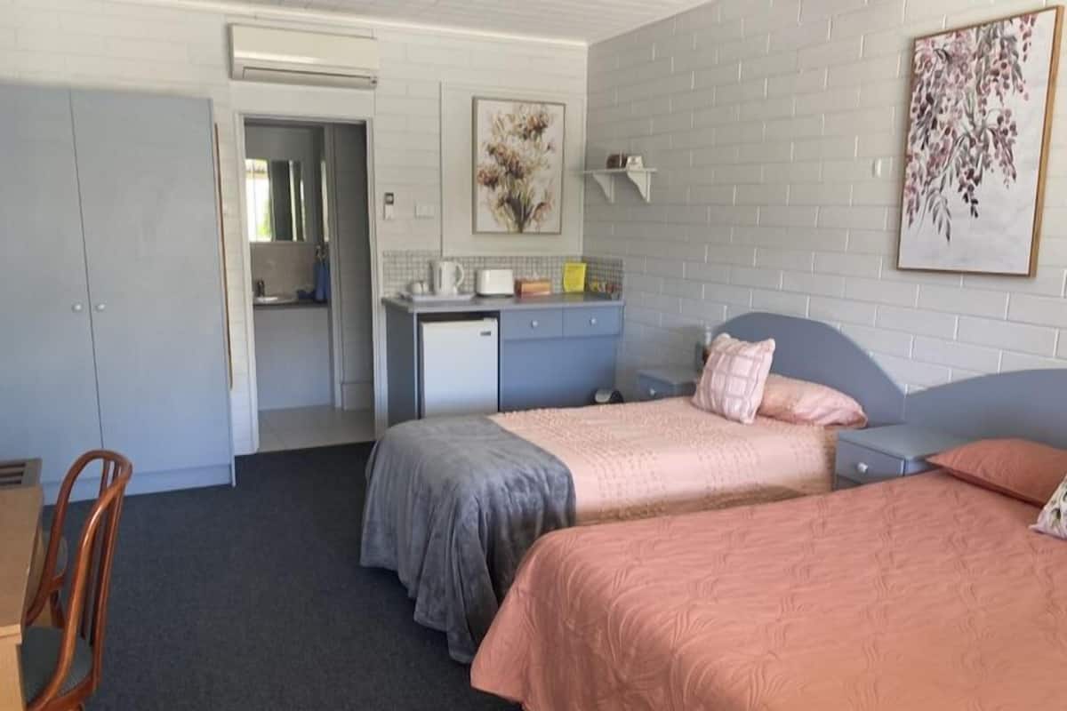 A bedroom with two beds, a desk, and a chair.