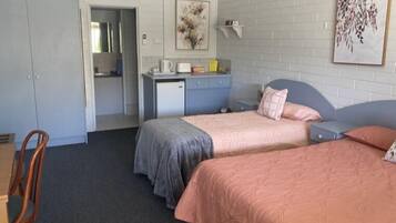 A bedroom with two beds, a desk, and a chair.