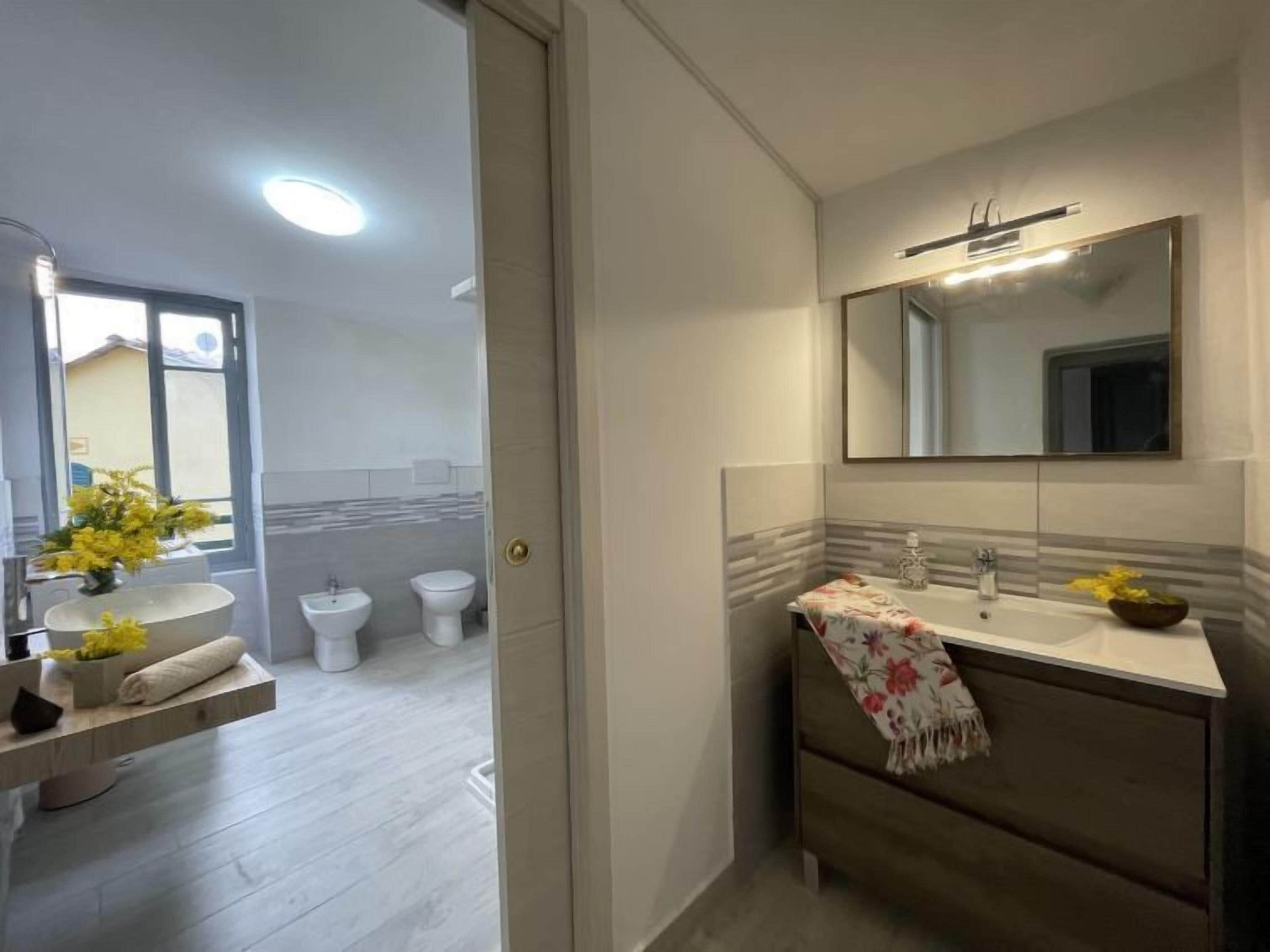 Un baño moderno con un espejo grande, un lavabo, un inodoro y una zona de ducha.