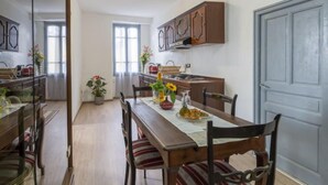 A dining area with a wooden table, chairs, and a kitchen in the background.