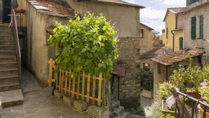 A narrow alleyway with stone buildings, a wooden fence, and a staircase leading to a door.