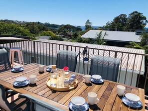 Une terrasse en bois avec une table préparée pour le thé, donnant sur un quartier résidentiel avec des maisons et des arbres.
