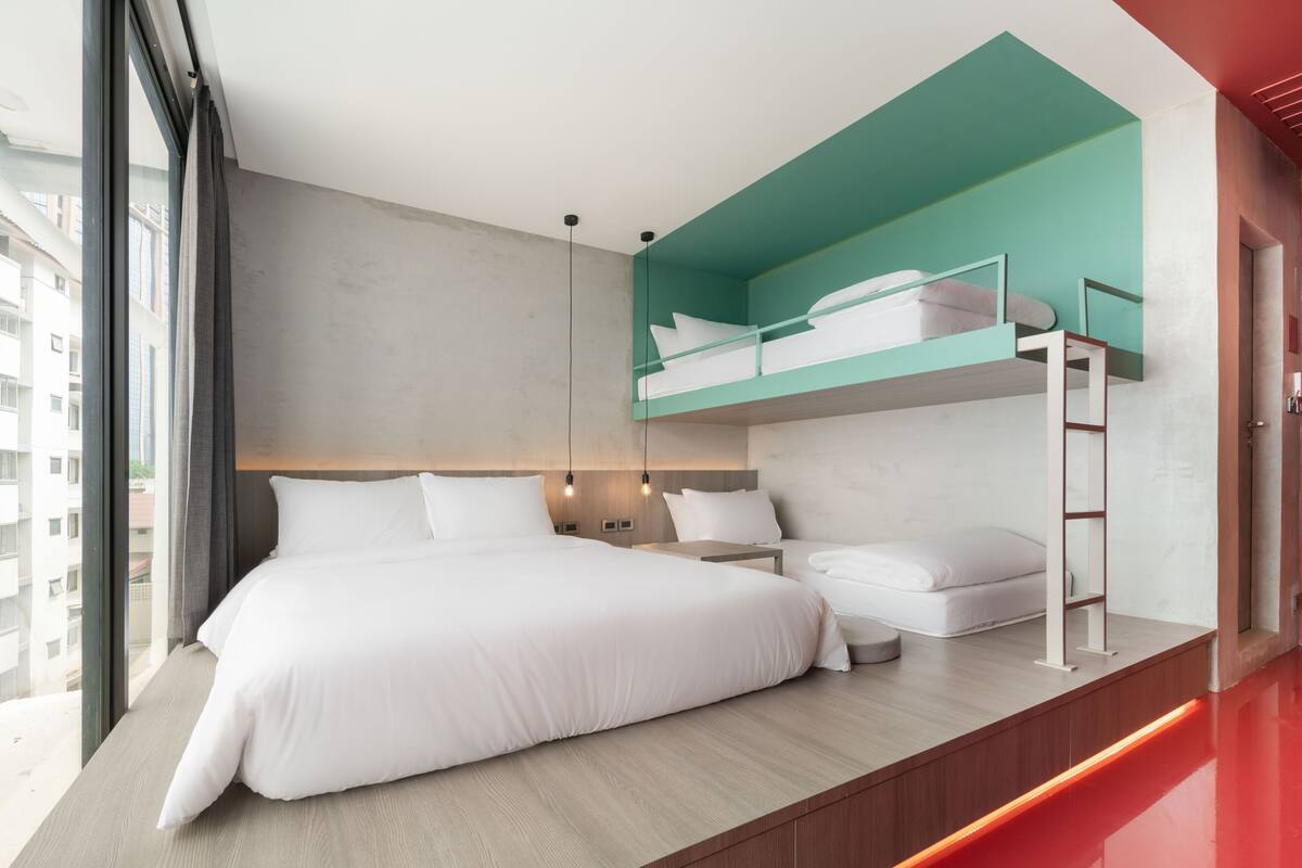 Una habitación de hotel moderna con una cama grande, una cama litera y vista a la ciudad.