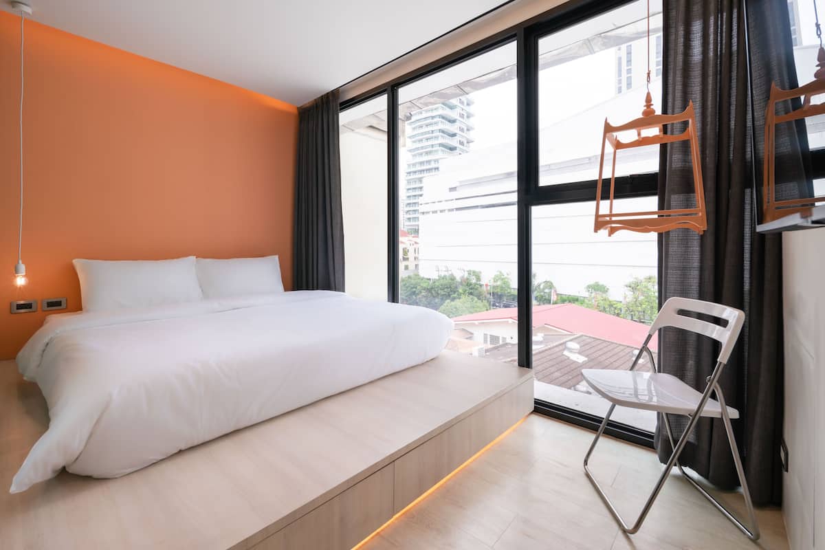 Un dormitorio moderno con una cama grande, vistas a la ciudad y una silla plegable.