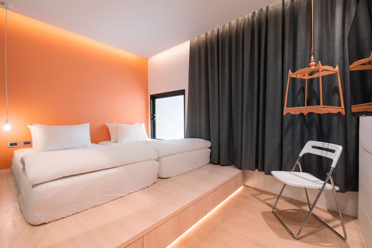 Un dormitorio moderno con cama, una silla y una ventana con cortinas.