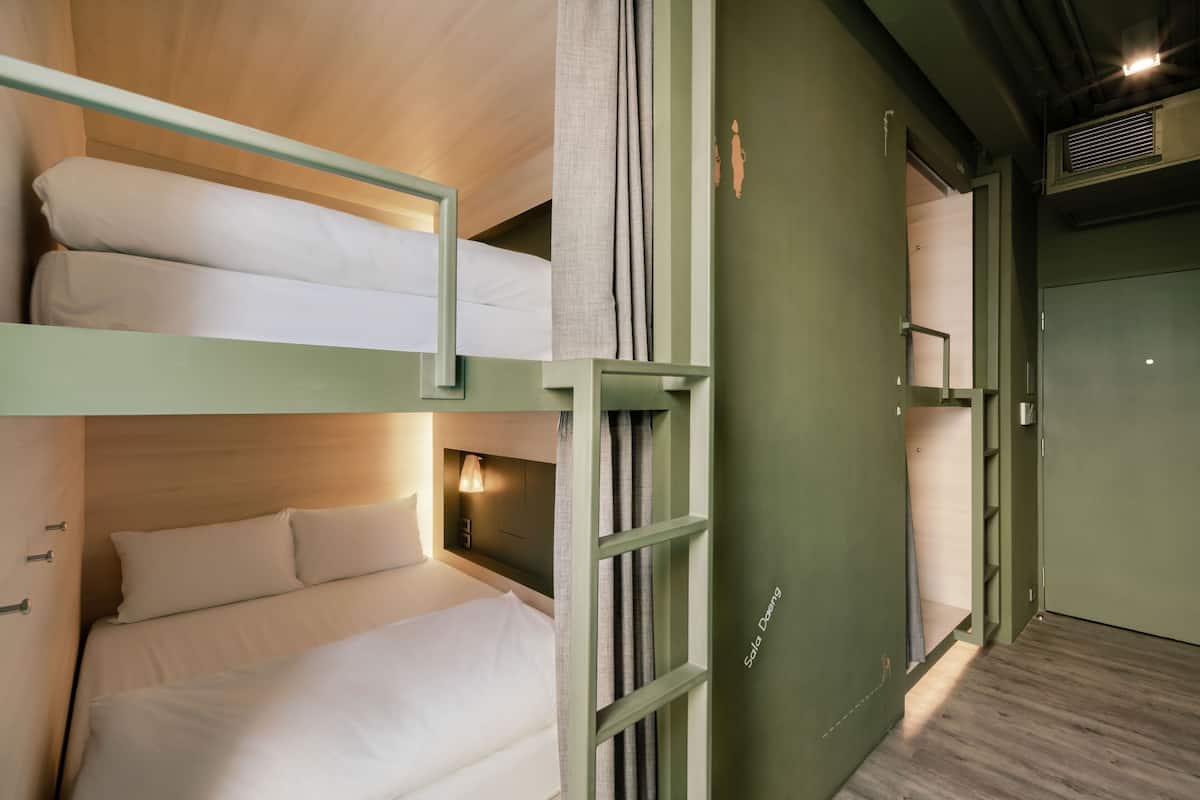 Habitación con literas, cabecera de madera, mesita de noche y estante en la pared.