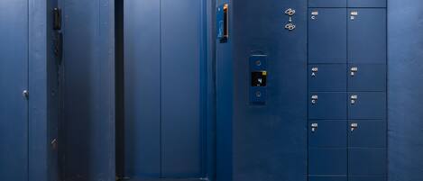 A blue elevator with numbered doors and a keypad.