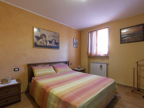 A bedroom with a bed, a nightstand, a window with curtains, and a radiator. - Lory House by Interhome (Pontedassio)