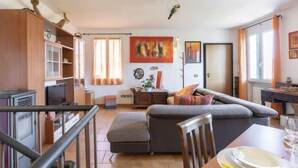 A modern living room with a grey sofa, wooden cabinets, and a dining area with a table set for two.