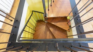 A spiral staircase with a wooden finish and metal handrails, leading to an upper floor.