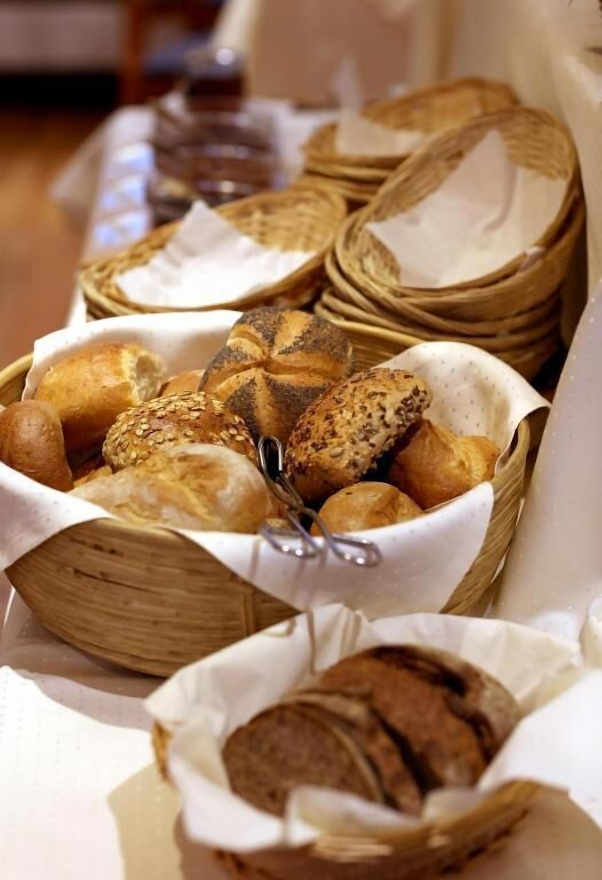 Ett urval av olika sorters bröd i korgar, inklusive fullkornsbröd, bröd med frön och eventuellt även surdegsbröd.