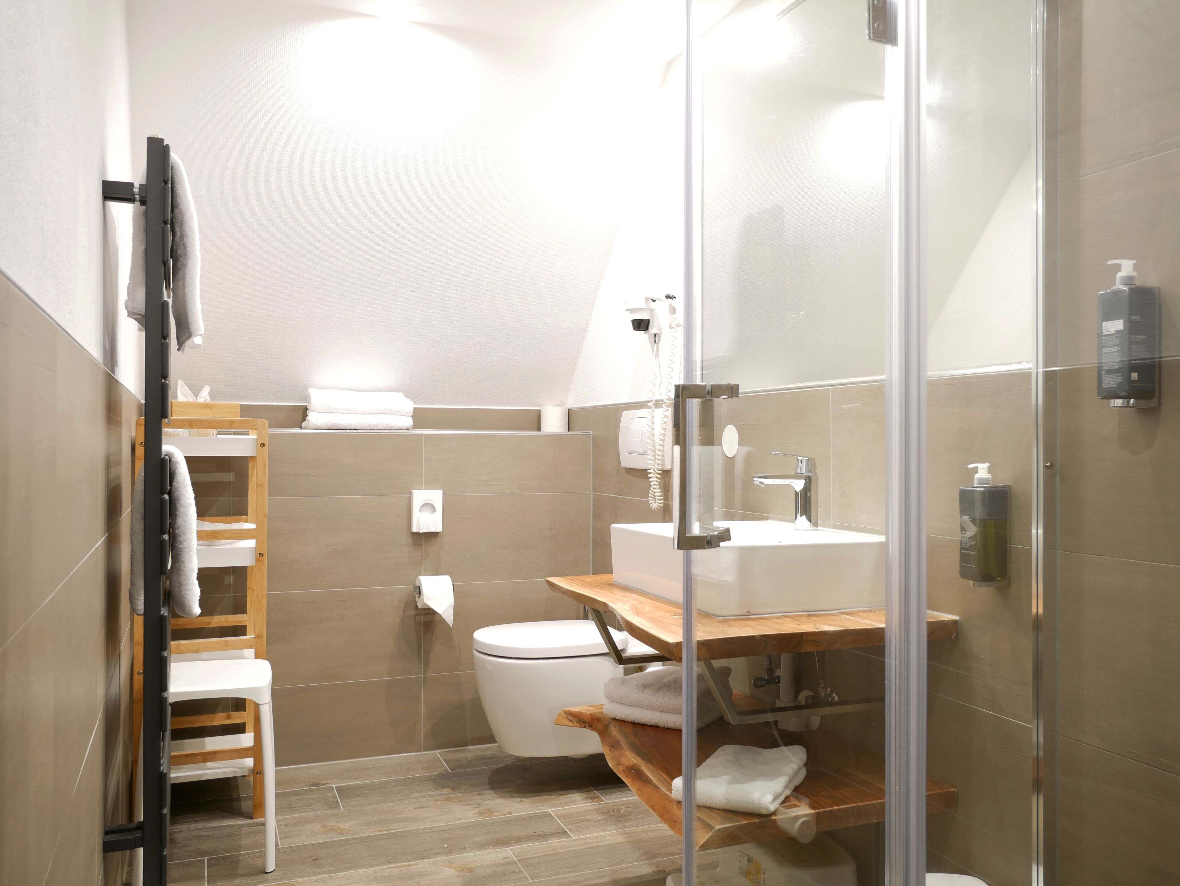 Un baño moderno con cabina de ducha de vidrio, tocador de madera y un inodoro.
