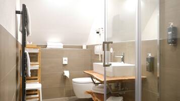 Un baño moderno con cabina de ducha de vidrio, tocador de madera y un inodoro.