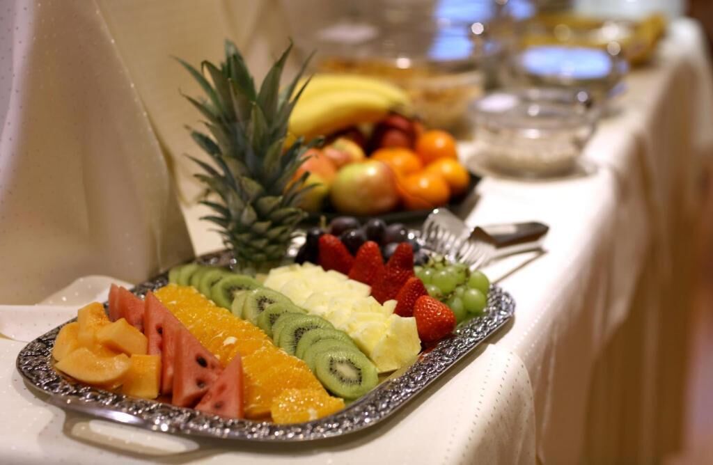 Une table de buffet proposant une variété de fruits, avec un ananas comme élément décoratif central.