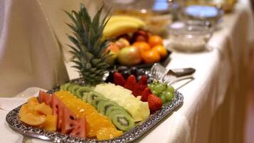 Une table de buffet proposant une variété de fruits, avec un ananas comme élément décoratif central.