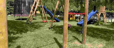 Un parque infantil con columpios, toboganes y una estructura para escalar.