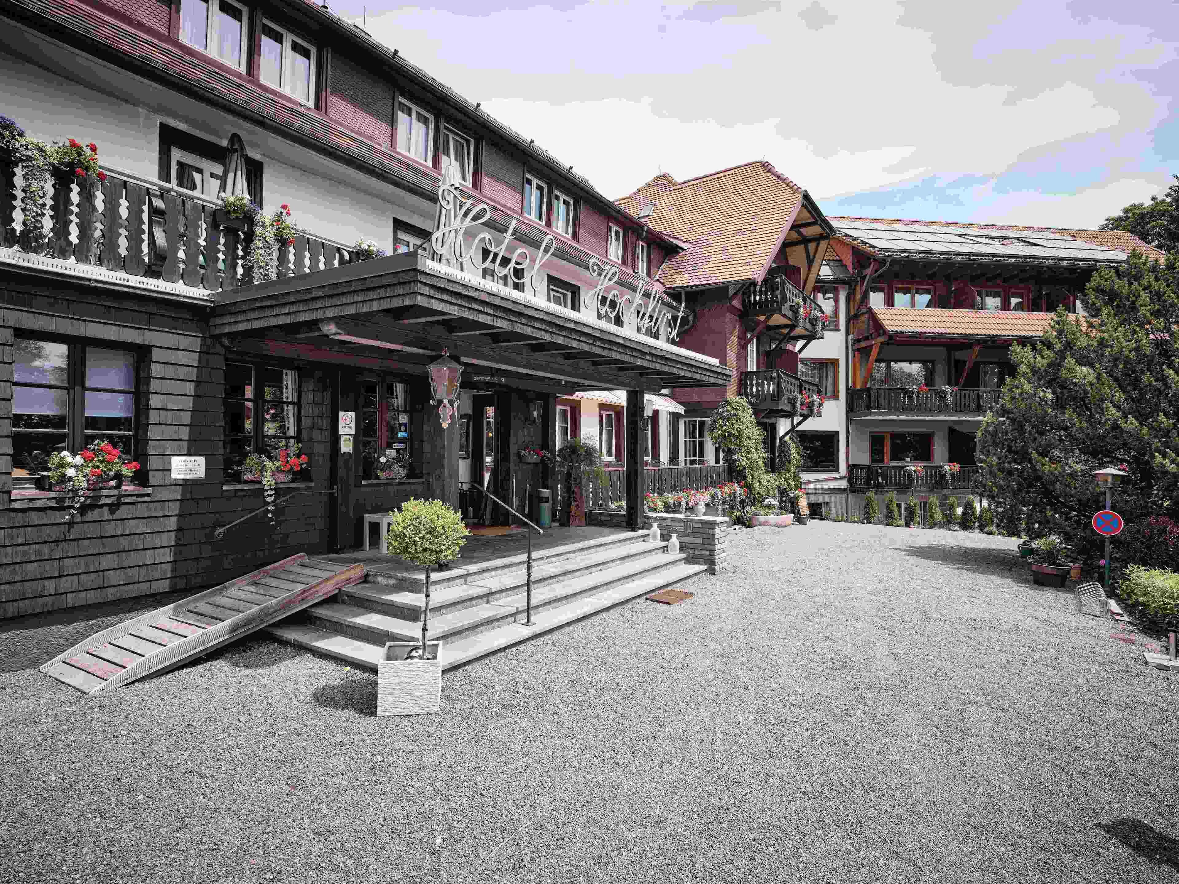 Un hotel con fachada de estilo europeo tradicional, un acceso cubierto y un patio de grava.