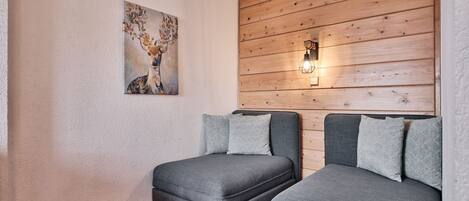 A room with two grey sofas, a red carpet, a wooden wall panel, and a wall-mounted light fixture.