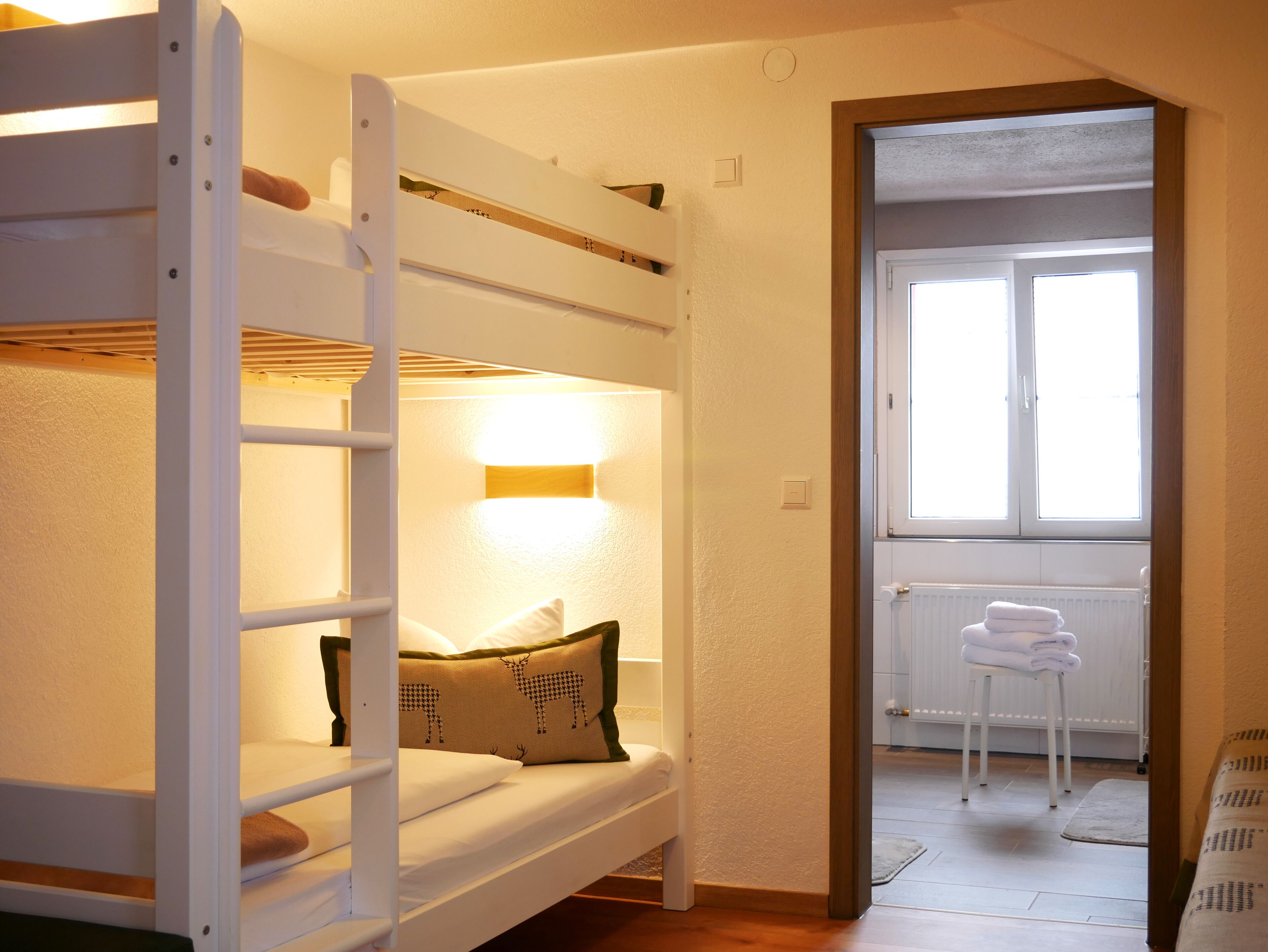 Una cama litera con cabecera y ventana que da a un radiador y toallas.