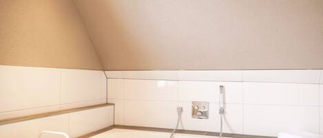 A modern bathroom with a freestanding bathtub, a towel rack, and a shelf with a tissue box.