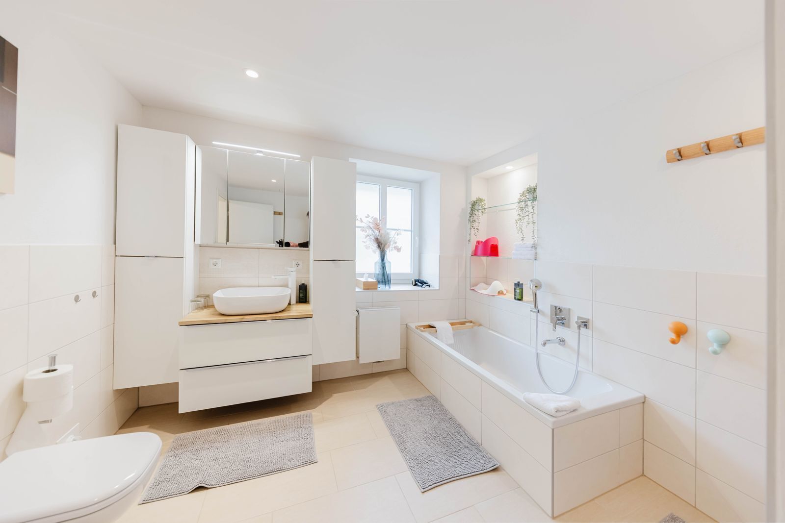 A modern bathroom with a toilet, sink, mirror, and bathtub.