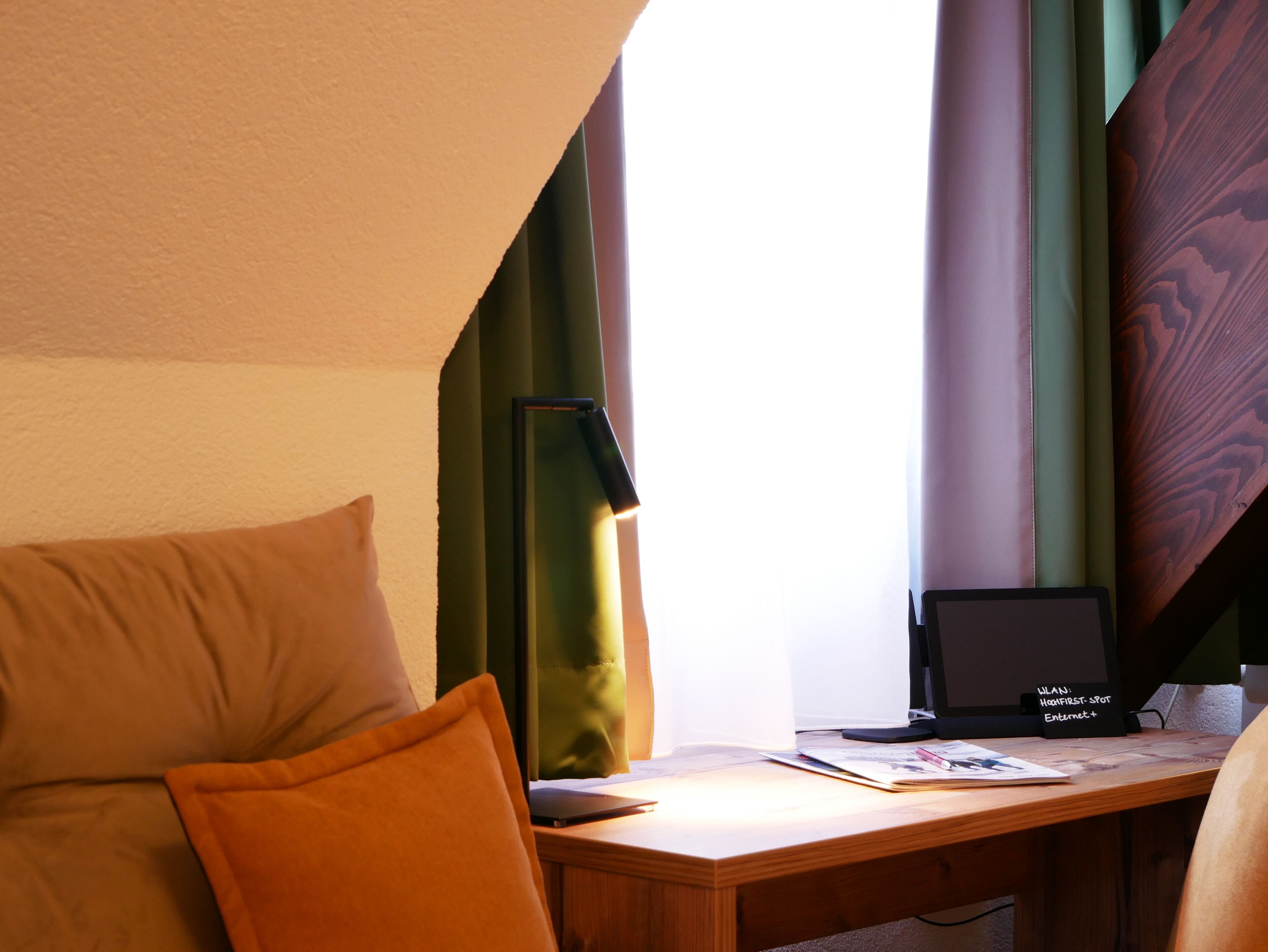 Ein Zimmer mit einem Holztisch, einem Laptop und einem Notizbuch.