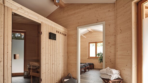 A wooden interior with a sliding door leading to a room with a bed and a small table. - Hotel Hochfirst (Lenzkirch)