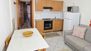 Una cocina compacta con armarios de madera, estufa a gas y refrigerador blanco.