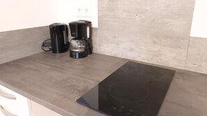 Una cocina con una placa de inducción negra y una cafetera sobre la encimera.