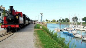 Höyryveturi raiteilla kanavan varrella, ja kanavassa on laivoja ankkuroituna.