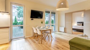A modern living room with a dining area, large windows, a flat-screen TV, and a green sofa. - Vacation apartment by the sea, vacation on the island of Usedom, apartment BALTYCKA 6 (Swinoujscie)