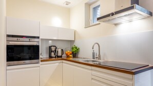 A modern kitchen with white cabinets, a stainless steel oven, a sink, and a window above the countertop. - Vacation apartment by the sea, vacation on the island of Usedom, apartment BALTYCKA 6 (Swinoujscie)