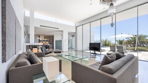 A modern living room with a glass coffee table, grey sofas, and a flat-screen TV. - Casa Henna (Faro)