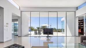 A modern living room with a glass coffee table, a leather sofa, and a flat-screen TV. - Casa Henna (Faro)
