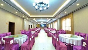 Ein Hotelzimmer mit langem Gang, mehreren runden Tischen und violetten Stühlen.