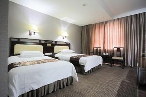 Une chambre d’hôtel avec deux lits, un bureau et une chaise.