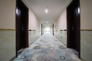 A long, narrow hotel corridor with doors on both sides and a patterned carpet. - Xiyu Yongsheng Hotel (Fuyun)