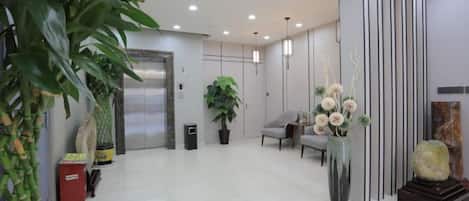Un vestíbulo moderno con mostrador de recepción, zona de estar y una planta grande en maceta.