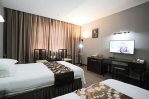 Une chambre d’hôtel avec deux lits, un bureau, une chaise, une télévision et des rideaux.